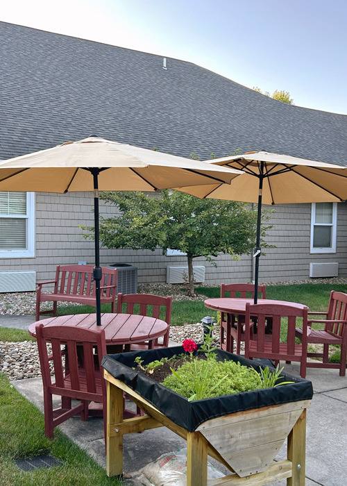 Lilies blooming in the garden at Hudson Grande Senior Living, next to white fencing and neatly edged landscaping.