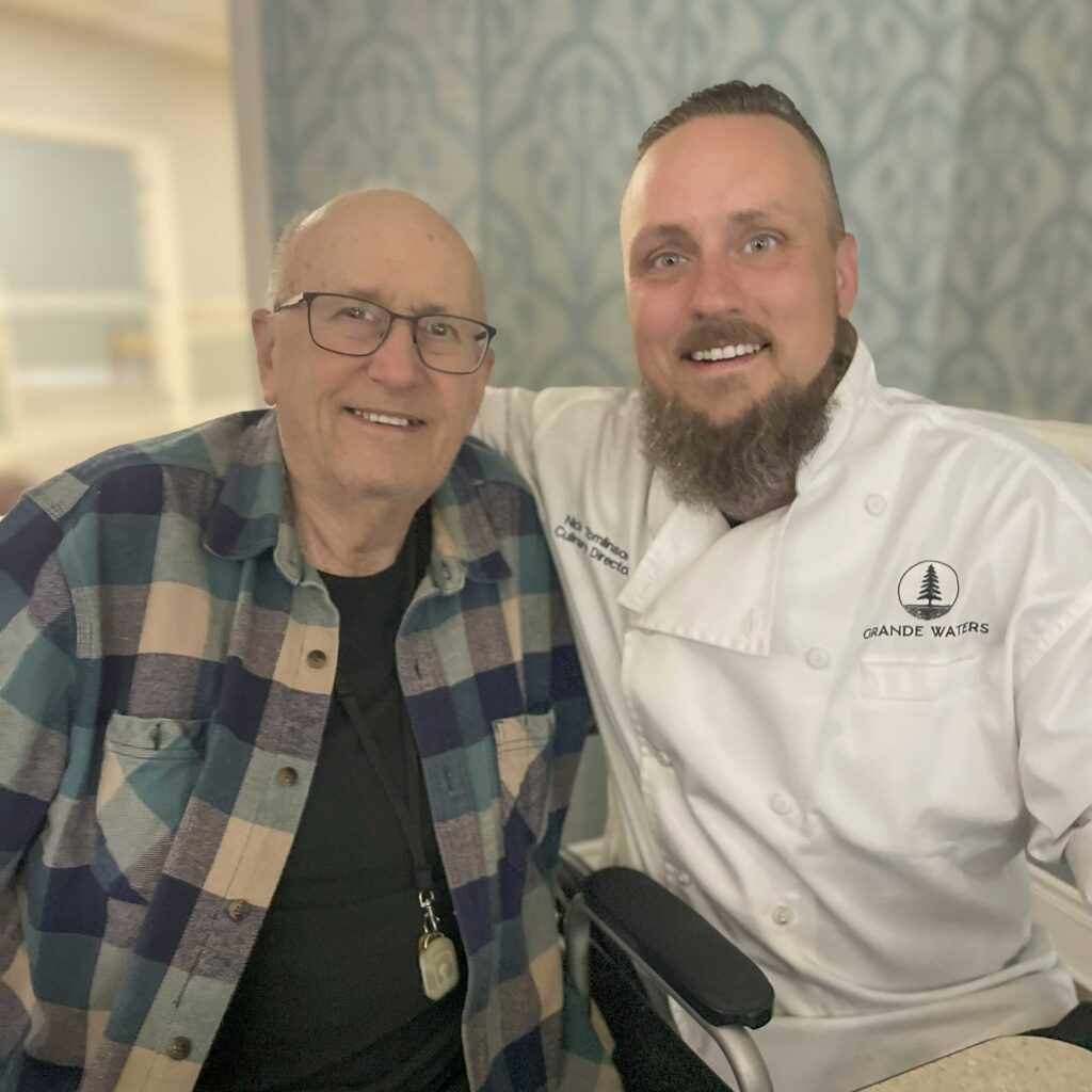 Senior resident and Culinary Director smile together, showing friendship and connection at Hudson Grande.