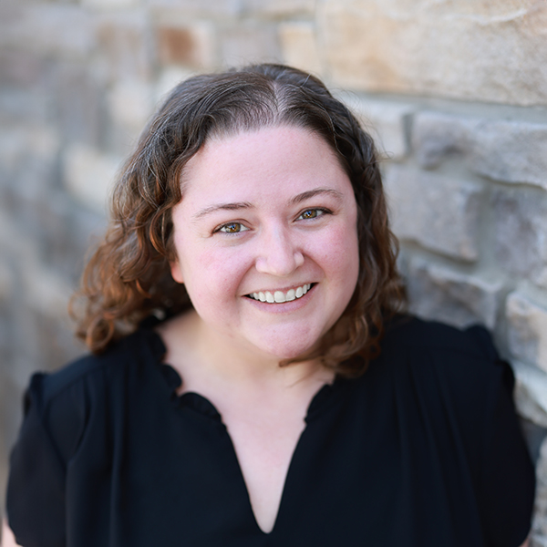 Katrese Barta Strong, Executive Director at Hudson Grande Senior Living, smiling outdoors in a black blouse against a stone wall.