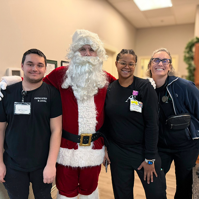 Team members smile brightly with Santa during a celebration at Hudson Grande Senior Living.